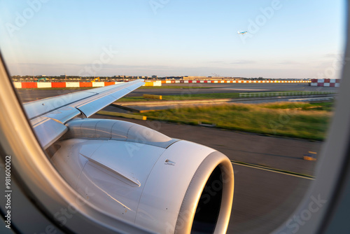 Wingview of a Modern Jet Aircraft Taxiing for Takeoff at Amsterdam Schiphol Airport in Evening Sunlight photo