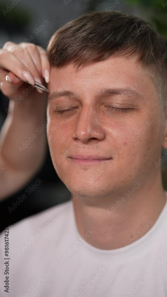 Vertical portrait of handsome metrosexual male looking relaxed and content getting eyebrows shaped at beauty salon. Close-up of positive man grooming in tranquil setting, promoting wellness. Vertical portrait of handsome metrosexual male looking relaxed and content getting eyebrows shaped at beauty salon. Close-up of positive man grooming in tranquil setting, promoting wellness.