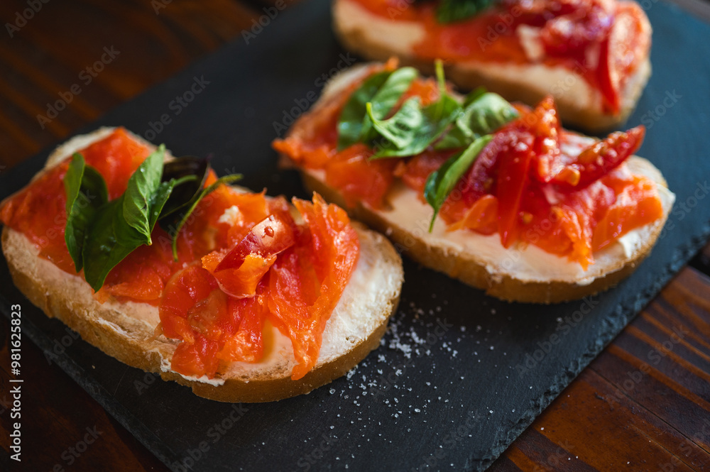 delicious juicy canapes of red fish, salmon on white bread with red tomato, on a dark background, selective focus, canape, quick snack delicious juicy canapes of red fish, salmon on white bread with red tomato, on a dark background, selective focus, canape, quick snack