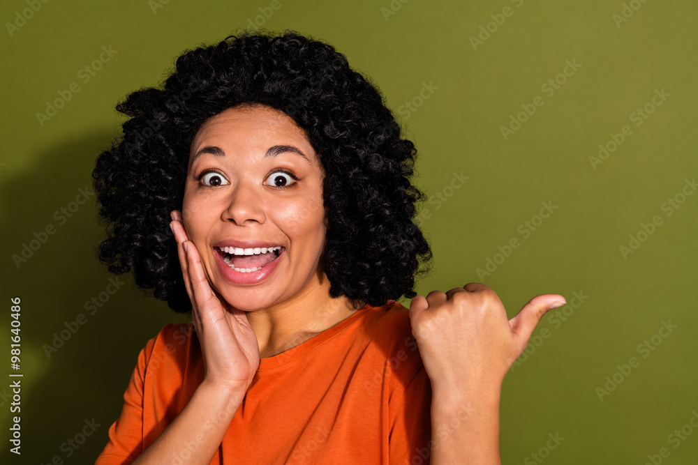 Photo portrait of lovely young lady amazed point empty space dressed stylish orange garment isolated on khaki color background Photo portrait of lovely young lady amazed point empty space dressed stylish orange garment isolated on khaki color background