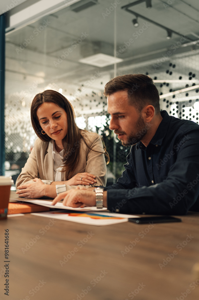 Colleagues sitting at boardroom with paperwork and doing statistics. Colleagues sitting at boardroom with paperwork and doing statistics.