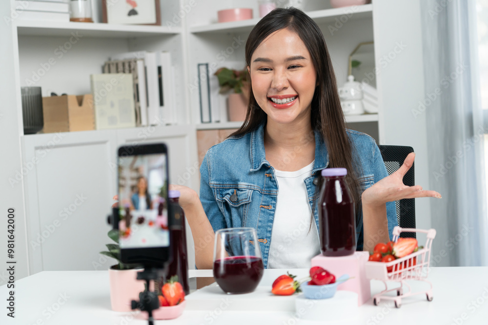 Smiling young beautiful Asian reviewing tasty mixed strawberry and cherry juice detox drinks, showing healthy product to promote for special promotion selling on social media online record. Stratagem. Smiling young beautiful Asian reviewing tasty mixed strawberry and cherry juice detox drinks, showing healthy product to promote for special promotion selling on social media online record. Stratagem.