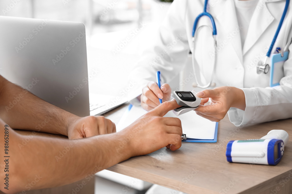 Young man with pulse oximeter and doctor in clinic, closeup Young man with pulse oximeter and doctor in clinic, closeup