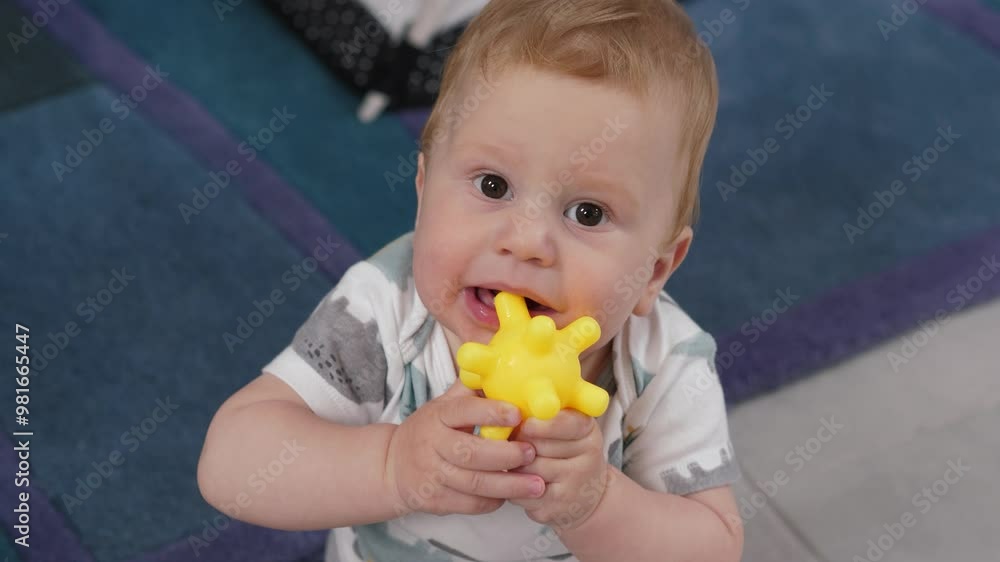 Super cute infant is joyfully playing with a bright yellow starshaped toy. Baby bites the toy, showcasing their natural curiosity and exploration in a cheerful and playful indoor environment Super cute infant is joyfully playing with a bright yellow starshaped toy. Baby bites the toy, showcasing their natural curiosity and exploration in a cheerful and playful indoor environment