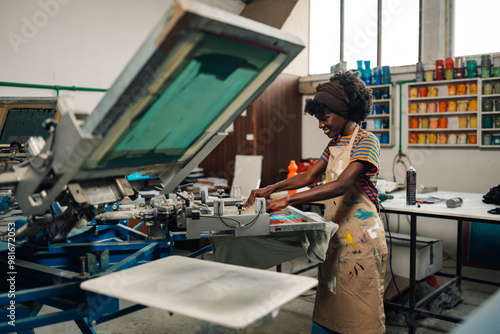 Fotografia Diverse printing shop worker using squeegee for silkscreen printing