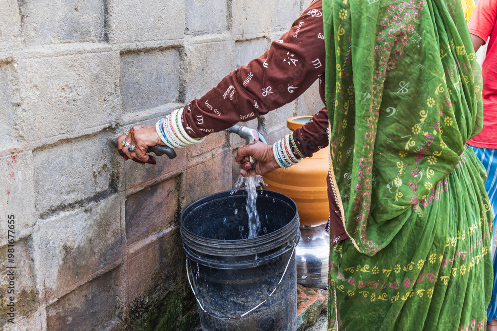 Filling a bucket with drinking water at a public tap.