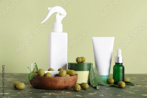 Set of natural cosmetic products and green olives on color table