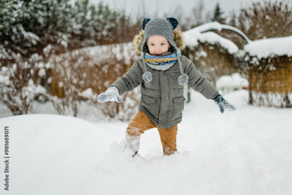 Adorable little boy having fun on snowy winter day. Cute child wearing warm clothes playing in a snow. Adorable little boy having fun on snowy winter day. Cute child wearing warm clothes playing in a snow.