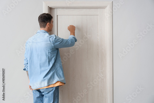 Photos Young man knocking on door in hall, back view