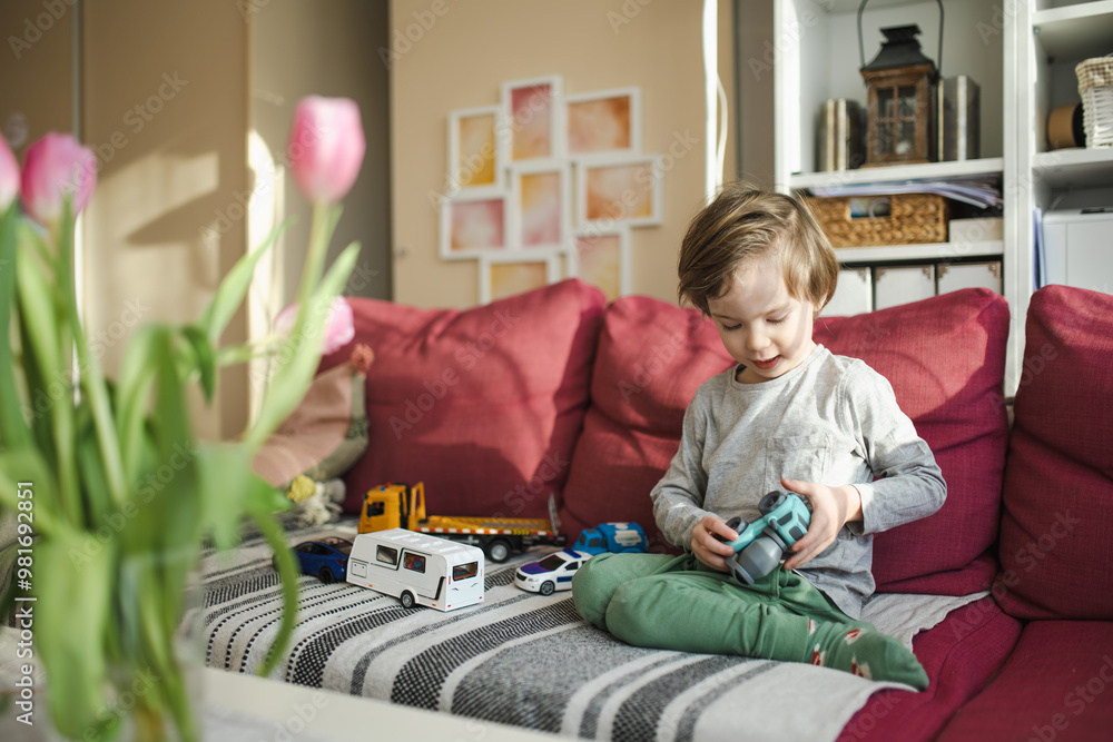 Obraz premium Cute boy playing with toy cars. Small child having fun with toys. Kid spending time in a cozy living room at home. Family leisure indoors.