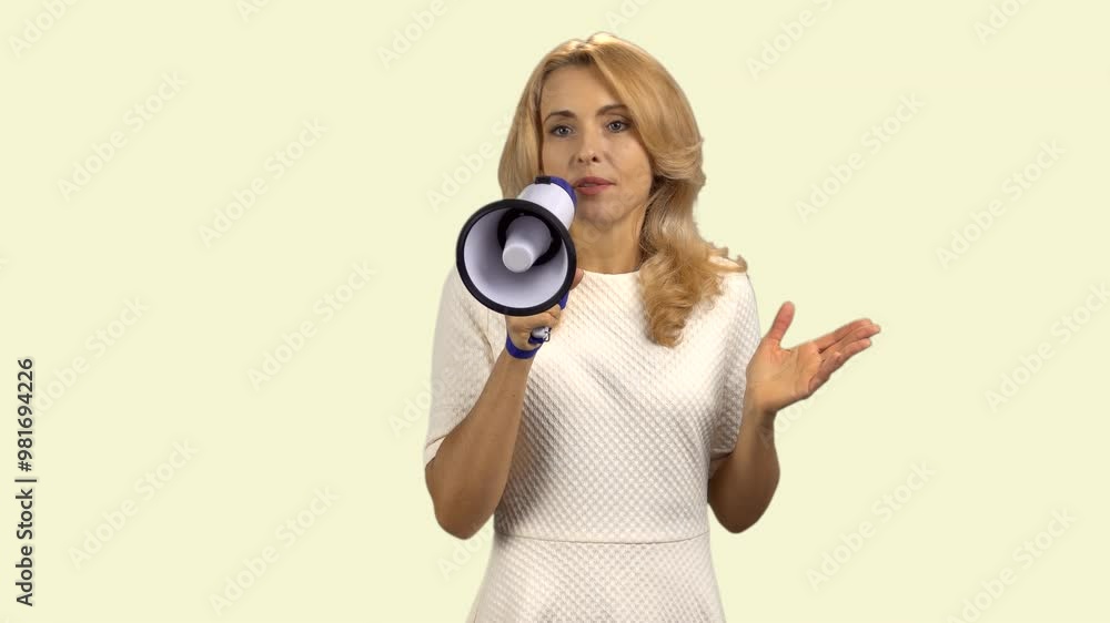 Portrait of a happy mature blonde woman giving a speech in megaphone. Isolated on light yellow. Portrait of a happy mature blonde woman giving a speech in megaphone. Isolated on light yellow.
