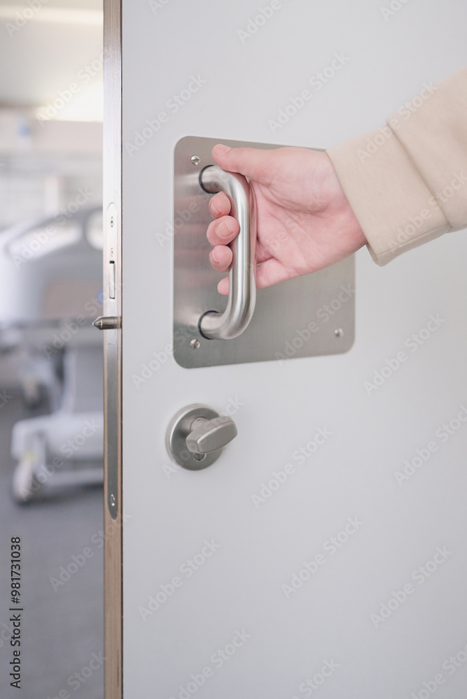 Fototapeta premium Hand of an unrecognizable woman pulling the handle of the sliding door to open and exit the bathroom of a hospital room