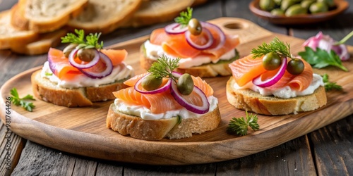 Smoked salmon canapés, arranged on a rustic wooden platter, topped with cream cheese, thinly sliced red onion, and capers, served with toasted baguette slices and a side of pickled cucumber slices.