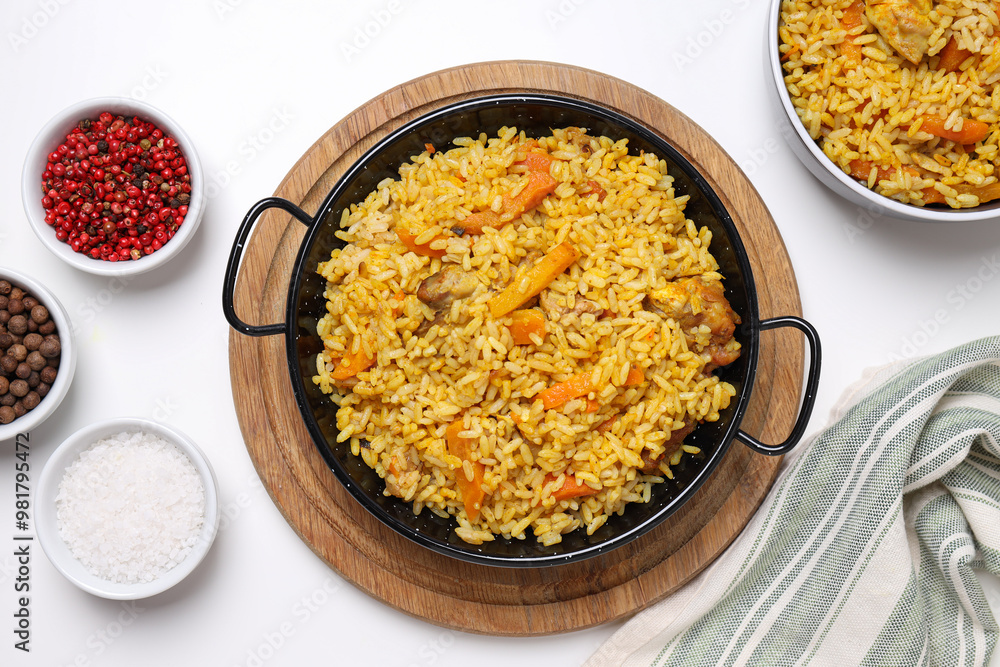 Pilaf in bowl and frying pan, spices and towel on white background, top view Pilaf in bowl and frying pan, spices and towel on white background, top view