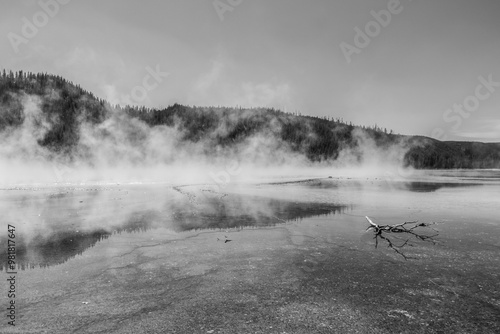 Dramatic black and white photograph of hot steam rising from the surface of the prismatic springs located at the mid way basin in Yellowstone national park in Wyoming.