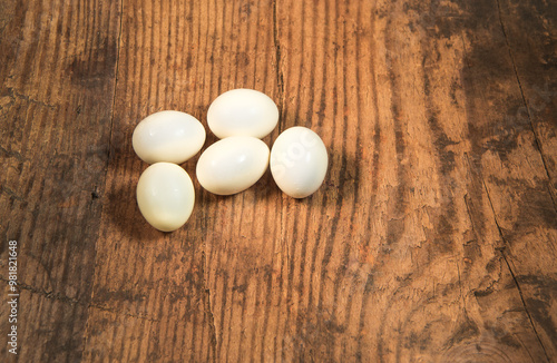 Peeled fresh organic eggs isolated on a rustic wooden table with advertising space. photo