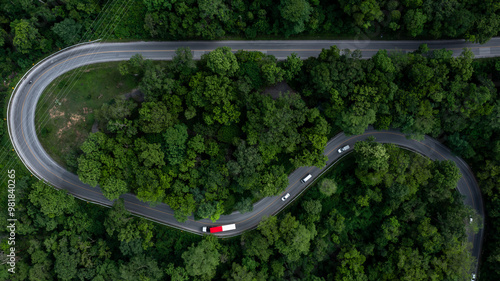 Aerial view car drive in green tree forest road winding road through the forest, Car drive on asphalt road between green tree forest, Electric vehicle EV car drive on asphalt road green tree forest.