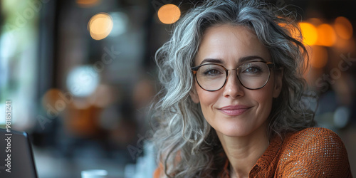 Woman with gray hair and glasses smiles at the camera.