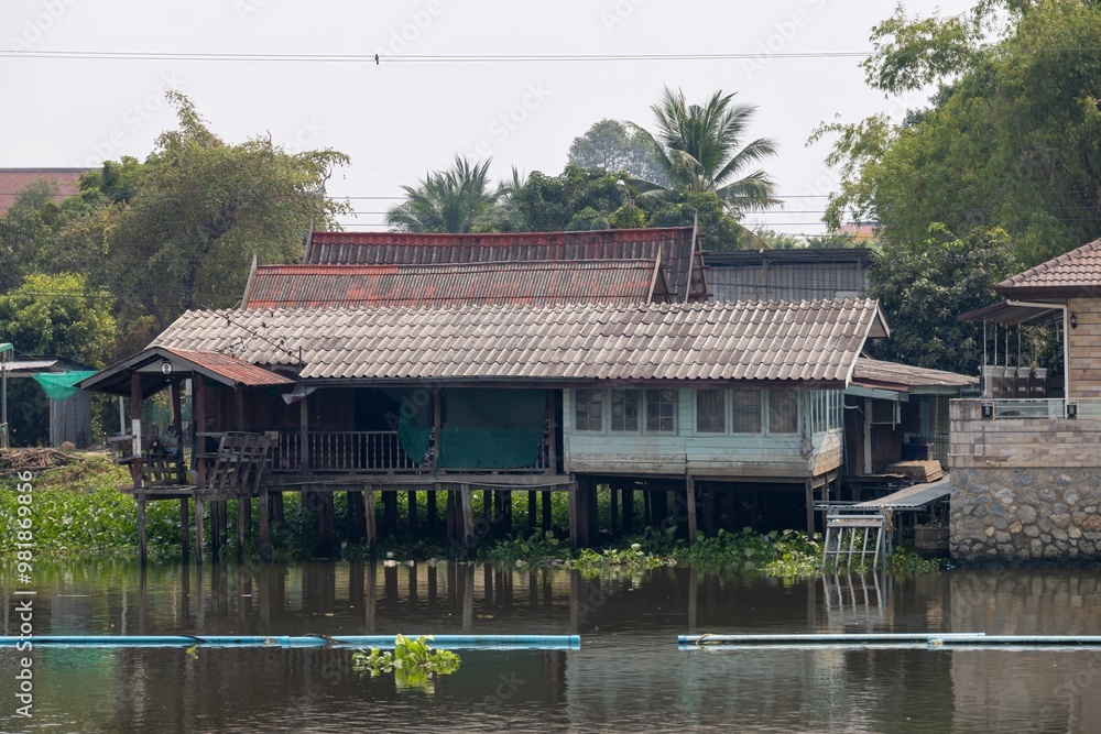 A traditional wooden house on stilts by a river, surrounded by lush ...