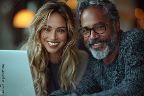 Smiling couple looking at laptop screen.