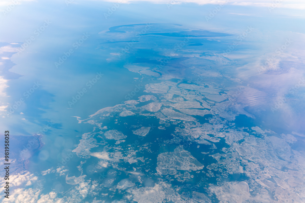 Fototapeta premium View from the airplane window at a beautiful blue clear sky, earth, sea and the airplane wing