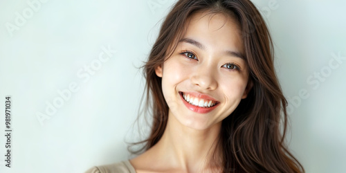 Closeup happy young asian woman in her 20s showing toothy smile, isolated on pastel blue background. Skin care, cosmetic surgery, healthy and white teeth, dental care. Dentistry concept.