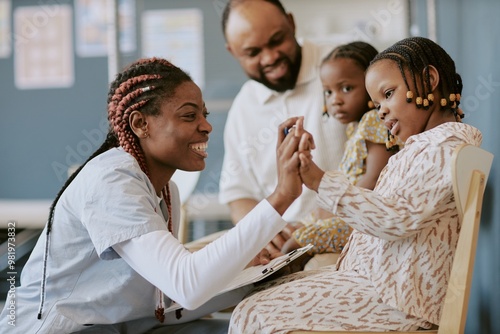 Behang African American nurse engaging with young child using educational toy at medica