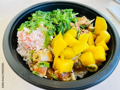 Poke Bowl topped with seaweeds and fresh mango chunks. photo