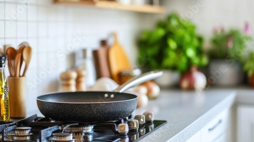 A modern kitchen scene featuring a frying pan on a stove with various kitchen tools and plants.