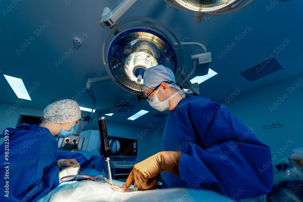 Surgeons in a modern heart surgery room. A team of surgeons conducts a delicate heart surgery in a well-equipped operating room during a busy surgical session. Surgeons in a modern heart surgery room. A team of surgeons conducts a delicate heart surgery in a well-equipped operating room during a busy surgical session.