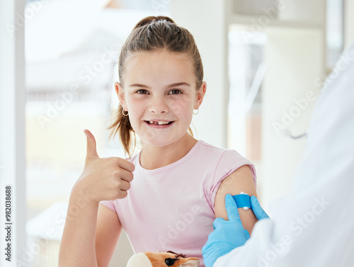 Thumbs up, girl and happy with band aid as patient at clinic for immunization or vaccine for virus. People, doctor and kid in portrait for injection as prevention for disease and treatment review