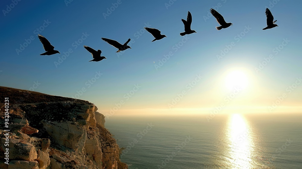 Fototapeta premium Birds flying over a serene ocean sunset.