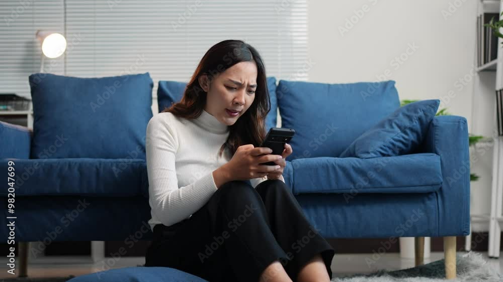 Happy Asian woman relaxing on sofa and playing with mobile phone. Attractive woman watching movie, chatting online with e-commerce shopping via mobile application at living room at home. Happy Asian woman relaxing on sofa and playing with mobile phone. Attractive woman watching movie, chatting online with e-commerce shopping via mobile application at living room at home.