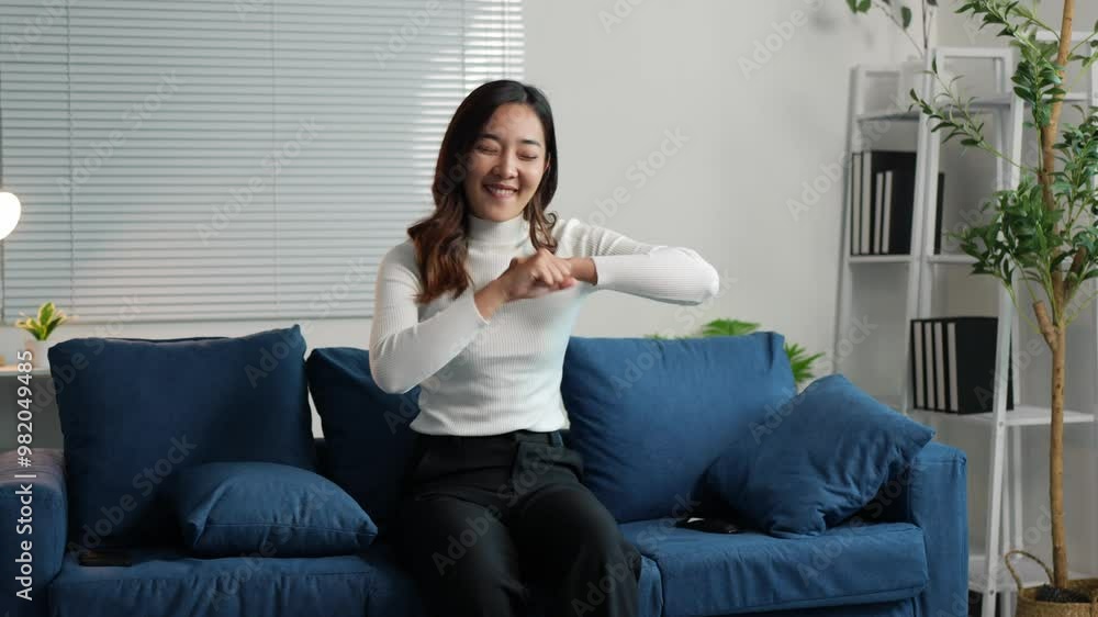 Young Asian woman dancing on sofa in living room at home. Smiling attractive woman happy and relaxed on vacation from work. Lifestyle concept, fun in life. Young Asian woman dancing on sofa in living room at home. Smiling attractive woman happy and relaxed on vacation from work. Lifestyle concept, fun in life.