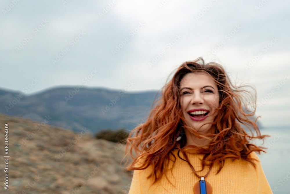 Portrait windswept hair happy woman against a backdrop of mountains and sea. Daylight illuminates the tranquil outdoor setting Portrait windswept hair happy woman against a backdrop of mountains and sea. Daylight illuminates the tranquil outdoor setting