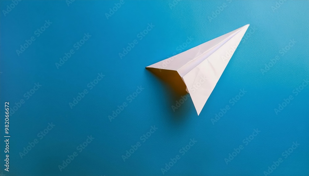 A simple paper airplane on a vibrant blue background, representing creativity, simplicity, and childhood memories. A simple paper airplane on a vibrant blue background, representing creativity, simplicity, and childhood memories.
