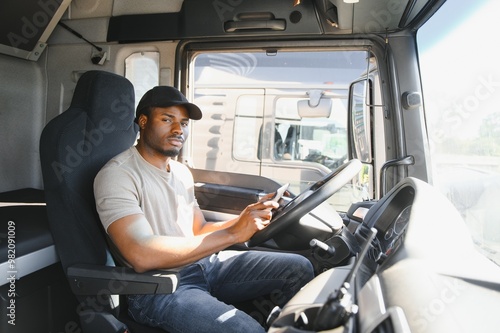 Truck driver sitting in truck, holding tablet, looking at cargo details, delivery schedule