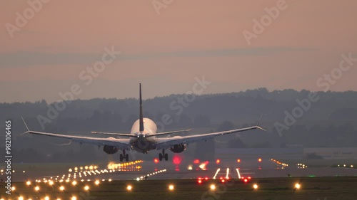 The plane lands at the airport. Commercial Jet Airplane Landing in airport runway at sunset. 