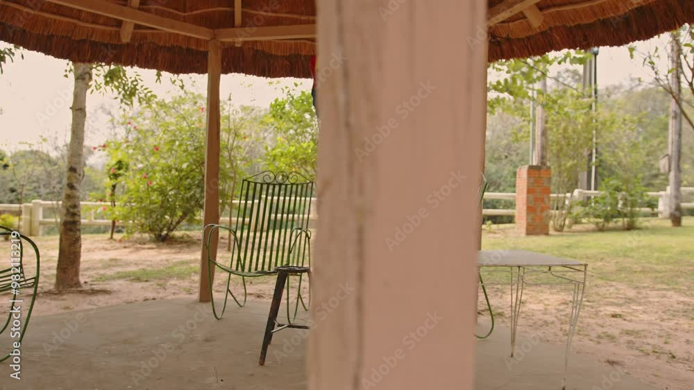 Thatched roof gazebo in a country house in Paraguay, with green iron chairs underneath, a white table, and a small table for terere on a beautiful Thatched roof gazebo in a country house in Paraguay, with green iron chairs underneath, a white table, and a small table for terere on a beautiful
