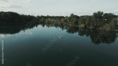 Drone over beautiful dark lake in germany flies over SUP Stand-Up Paddlers while camera is panning down on them! photo