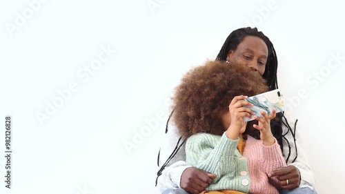 Happy african black family caring young father and smiling teeneger daughter relaxing on couch hugging looking on phone screen watching funny video online photo