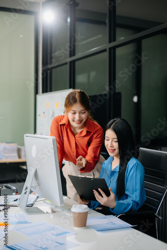 Two Asian businesswoman and man discuss investment project working and planning strategy with tablet laptop computer