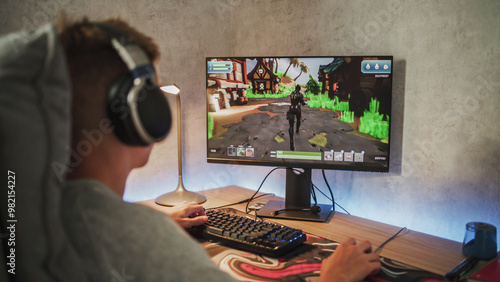 Billede på lærred Caucasian teenager wearing headphones plays online video game on PC, spends leisure time at home