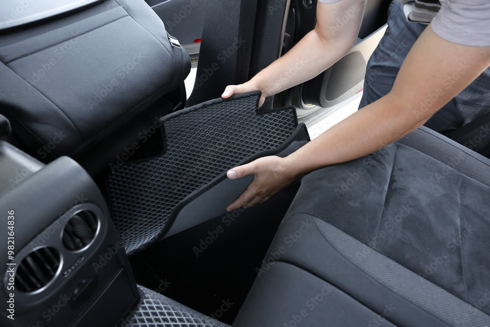 Man taking grey rubber car mat from auto, closeup Man taking grey rubber car mat from auto, closeup