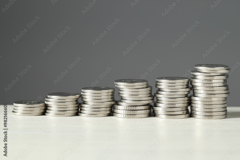 Stacked coins on white wooden table against grey background, closeup. Salary concept Stacked coins on white wooden table against grey background, closeup. Salary concept