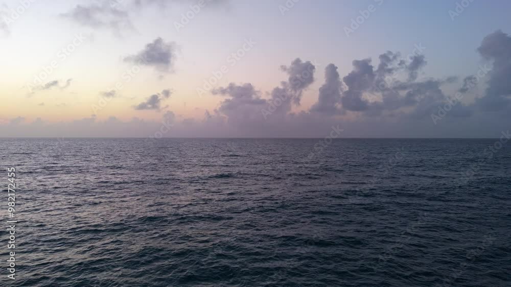 Slow-motion drone shot over the sea at sunrise, with waves in blue, orange, and navy colors. Clouds on the horizon, camera capturing the water from multiple perspectives. Slow-motion drone shot over the sea at sunrise, with waves in blue, orange, and navy colors. Clouds on the horizon, camera capturing the water from multiple perspectives.