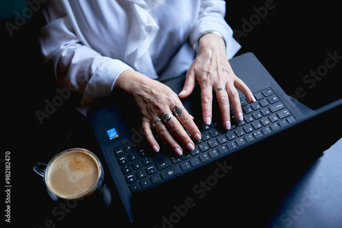  an elderly woman works in a cafe at a laptop photo