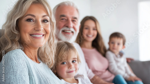 Large family gathered on the couch, three generations including grandparents and children, smiling and happy in a bright living room, family connection, copy space