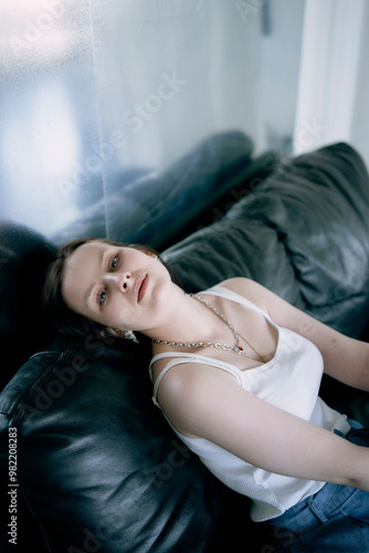 young teenage girl fighting brain cancer at photo shoot in studio, metal wall, reflection, black sofa