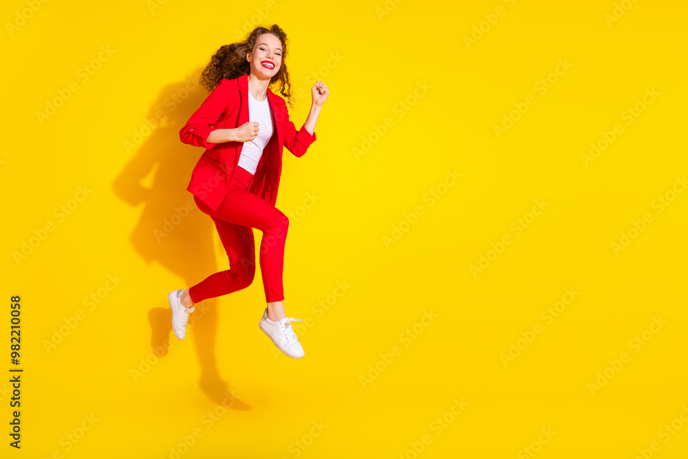 Full size photo of pretty young woman jump run empty space wear red suit isolated on yellow color background Full size photo of pretty young woman jump run empty space wear red suit isolated on yellow color background